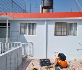 Detalle de mantenimiento residencial por M2 Arquitectos, mostrando el contraste entre la aplicación de pintura roja nueva en la cornisa y el tono azul claro original en los muros.