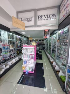 Interior de tienda mayorista de productos de belleza diseñada por M2 Arquitectos, con amplios pasillos, exhibidores organizados, iluminación LED brillante y piso de porcelanato negro pulido.