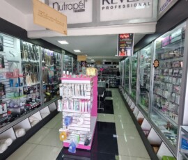 Interior de tienda mayorista de productos de belleza diseñada por M2 Arquitectos, con amplios pasillos, exhibidores organizados, iluminación LED brillante y piso de porcelanato negro pulido.